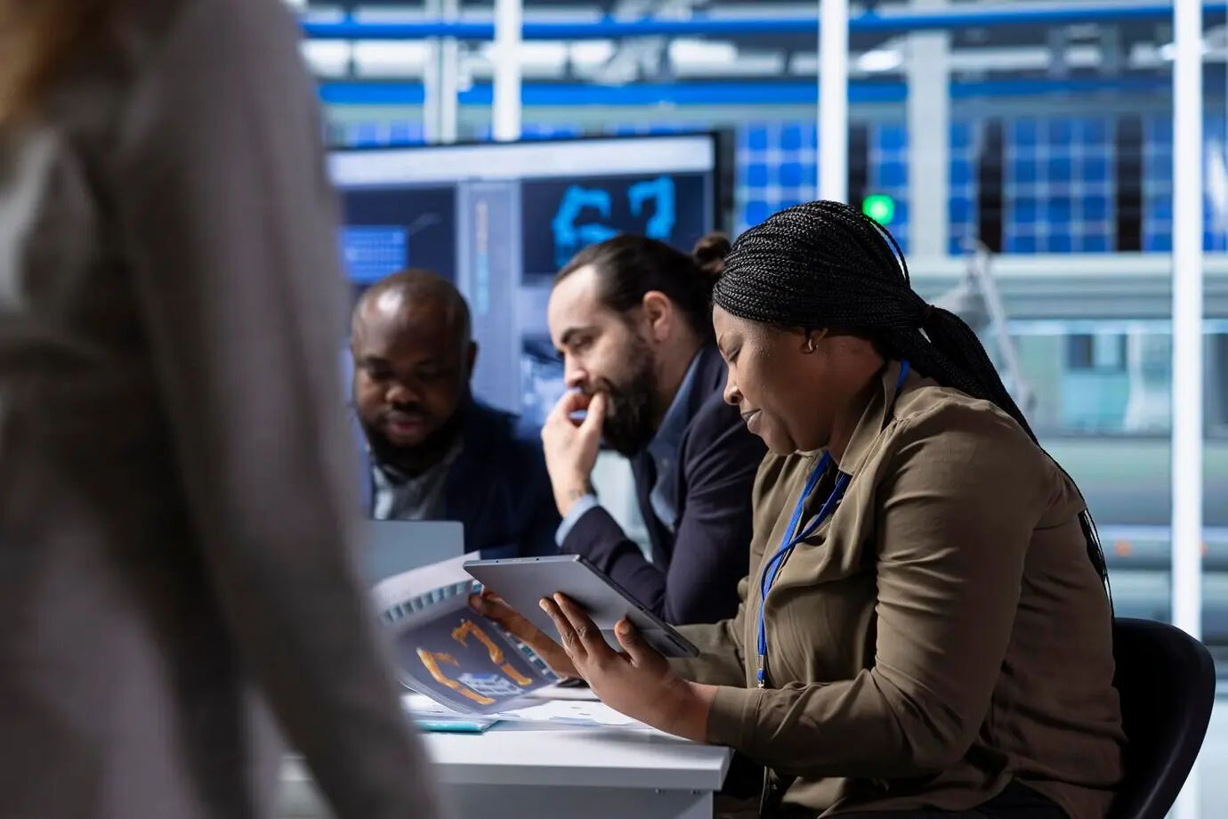 Руководители фотовольтаического завода, используя планшет, просматривают схемы.