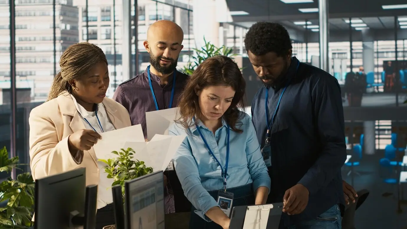 Портрет улыбающихся сотрудников в офисе, работающих вместе над завершением проекта.